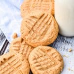 three ingredient peanut butter cookies stacked around a glass jar of milk