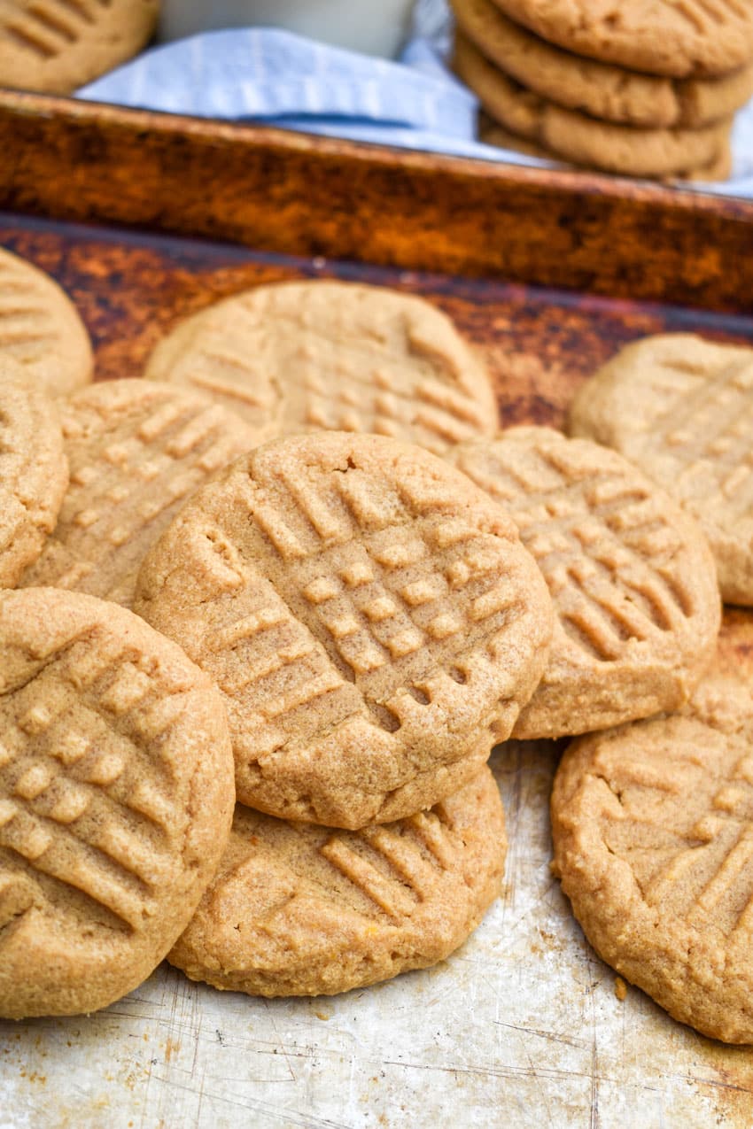 three ingredient peanut butter cookies piled together on a metal sheet pan