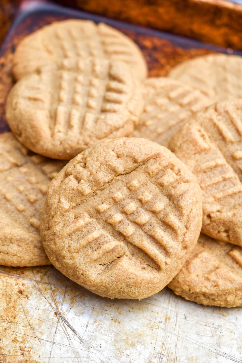 three ingredient peanut butter cookies piled together on a metal sheet pan