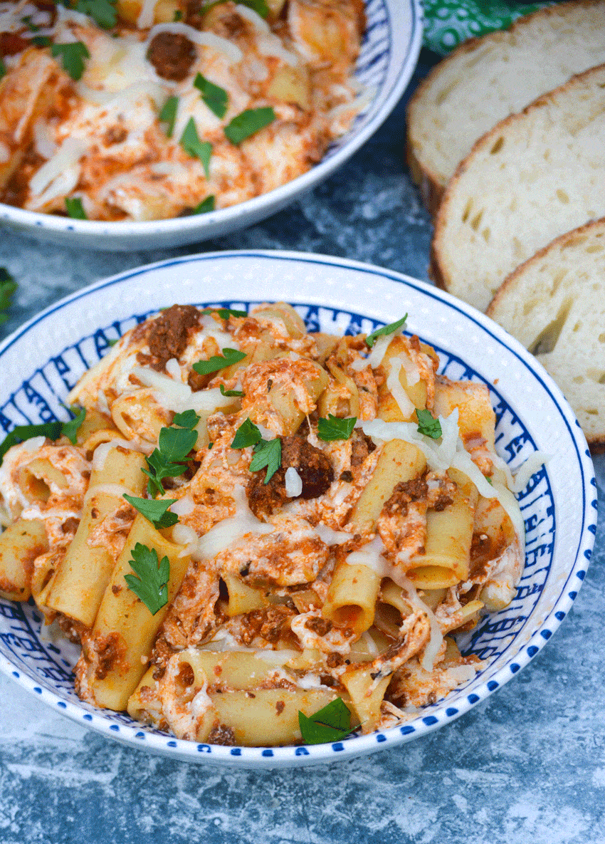 easy baked ziti recipe in two bowls with slices of crusty bread on the side