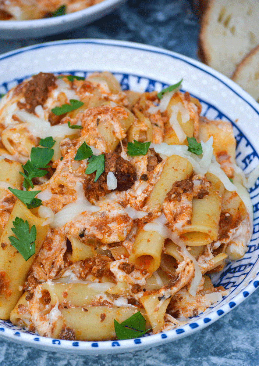 easy baked ziti recipe in two bowls with slices of crusty bread on the side