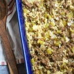 ground beef and rice casserole in a blue baking dish with a wooden spoon on the side