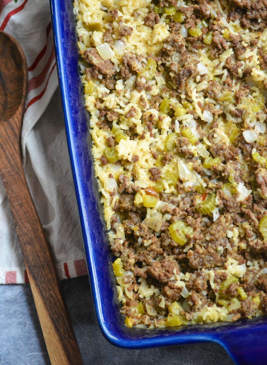 ground beef and rice casserole in a blue baking dish with a wooden spoon on the side