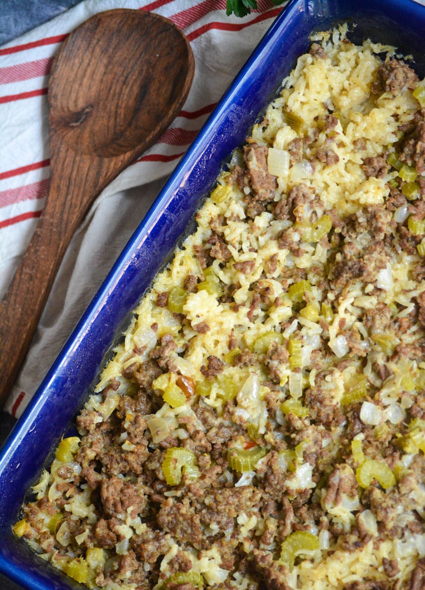 ground beef and rice casserole in a blue baking dish with a wooden spoon on the side