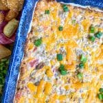 bacon cheeseburger dip in a blue baking dish surrounded by hamburger bun croutons