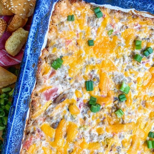 bacon cheeseburger dip in a blue baking dish surrounded by hamburger bun croutons