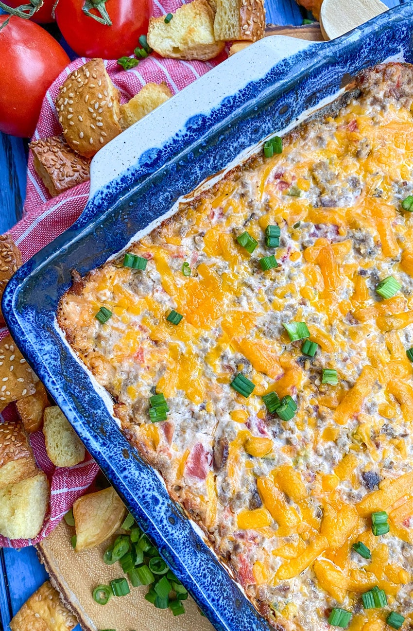 Cheeseburger Dip (With Hamburger Bun Croutons) bacon cheeseburger dip in a blue baking dish surrounded by hamburger bun croutons