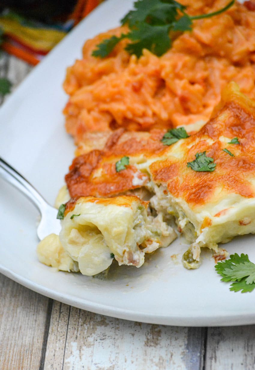 a silver fork on a white plate with cream cheese white chicken enchiladas