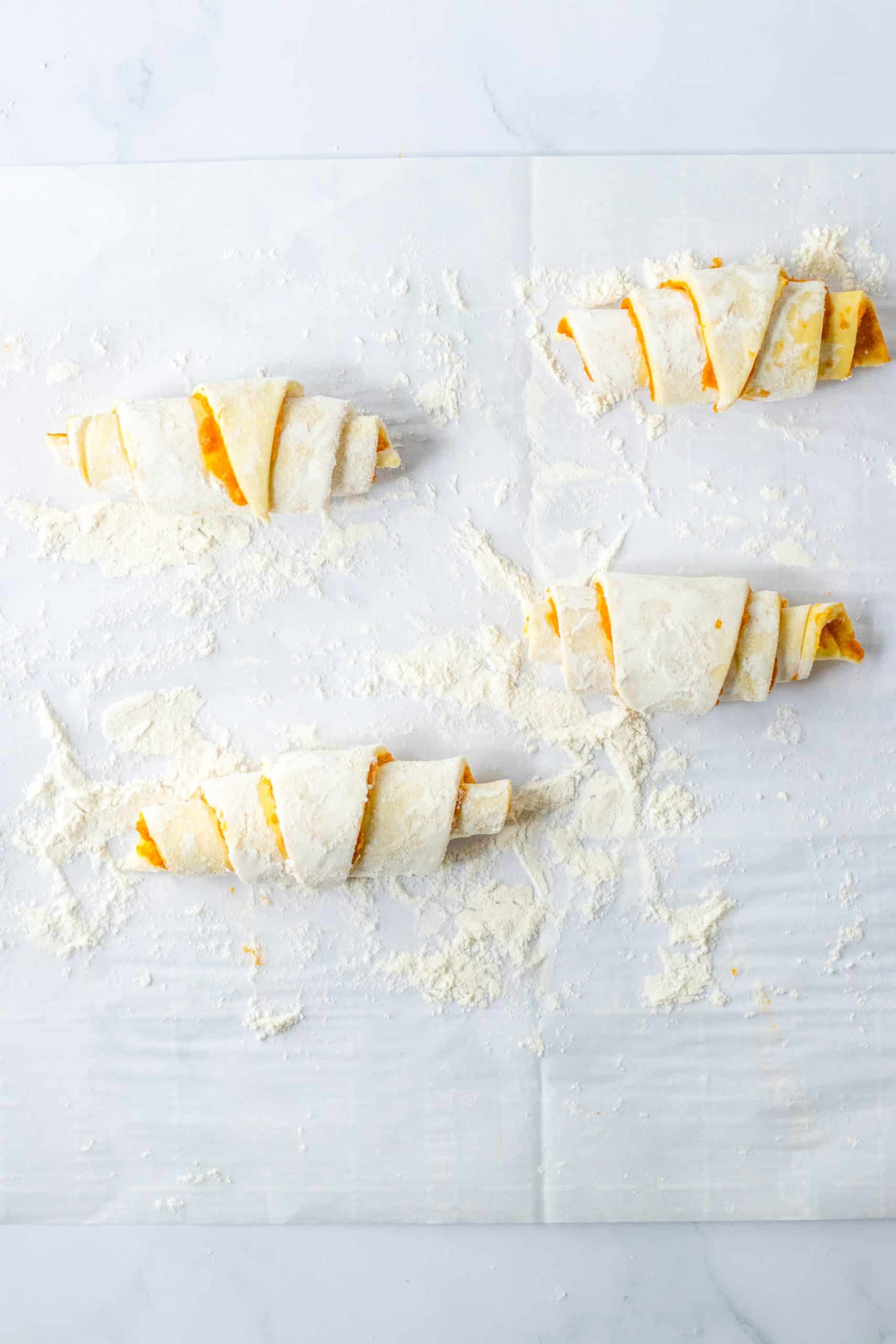 unbaked pumpkin pie crescent rolls on a floured sheet of parchment paper