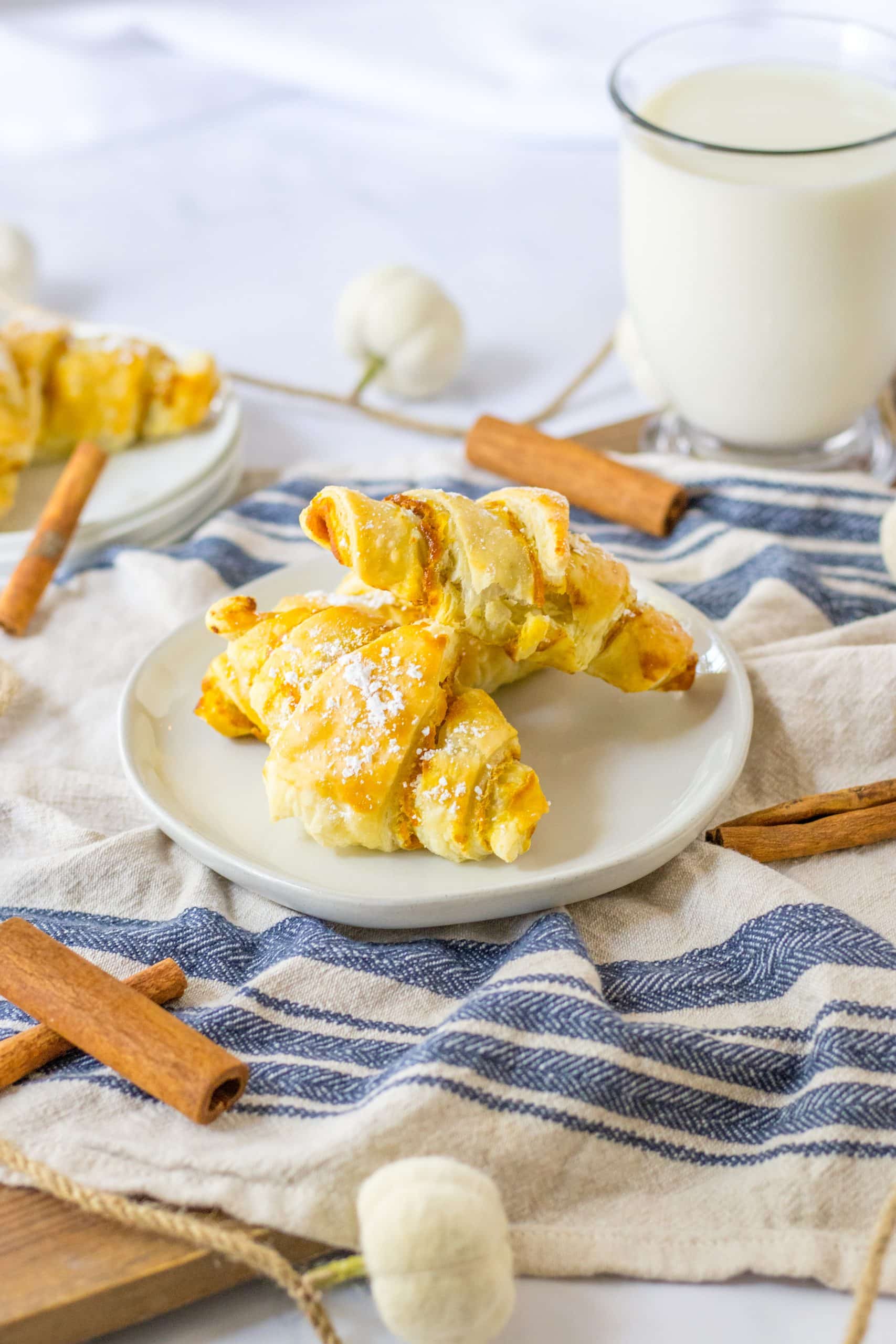 two pumpkin pie crescent rolls on a small white plate