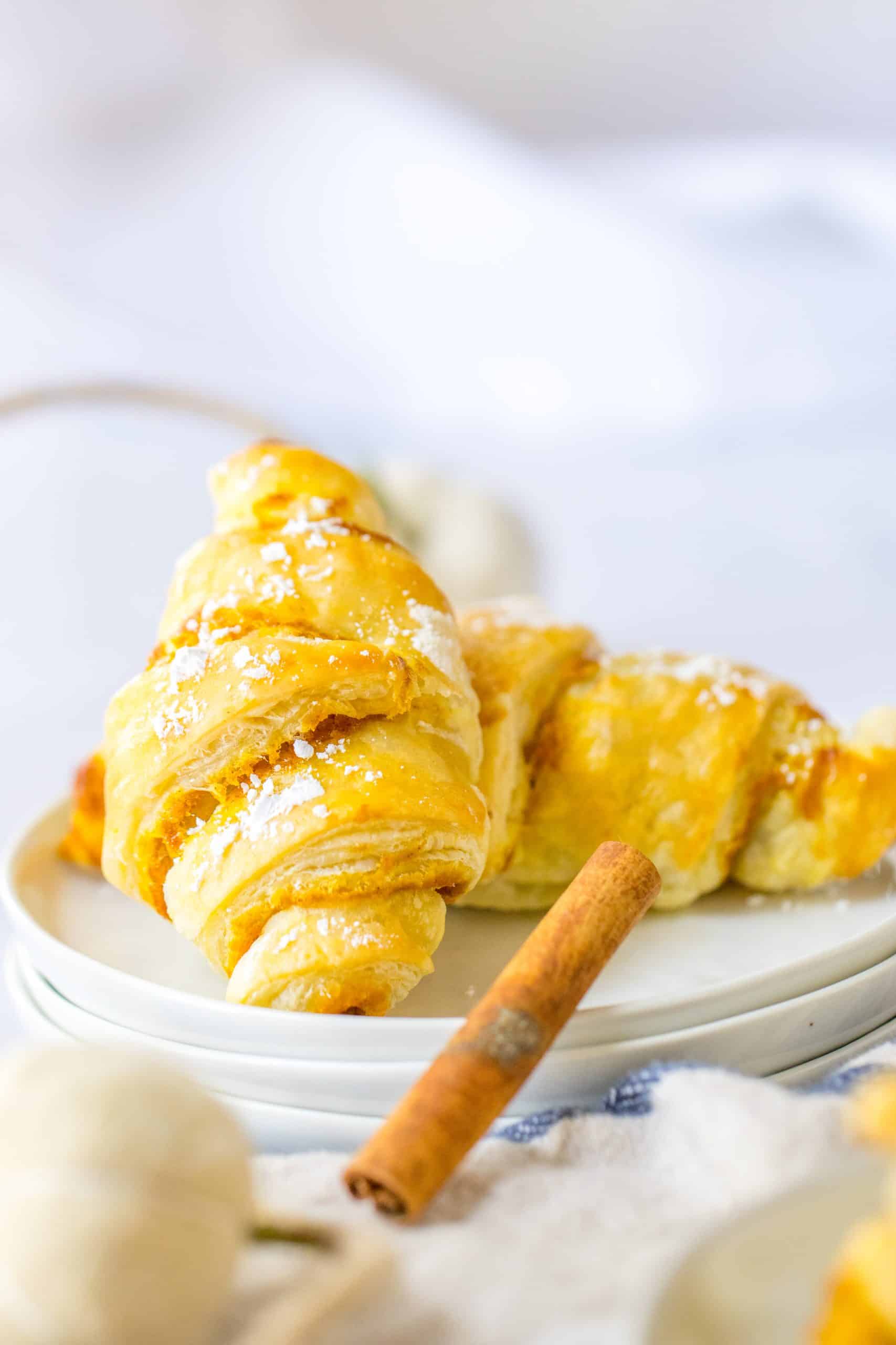 two pumpkin pie crescent rolls on a small white plate