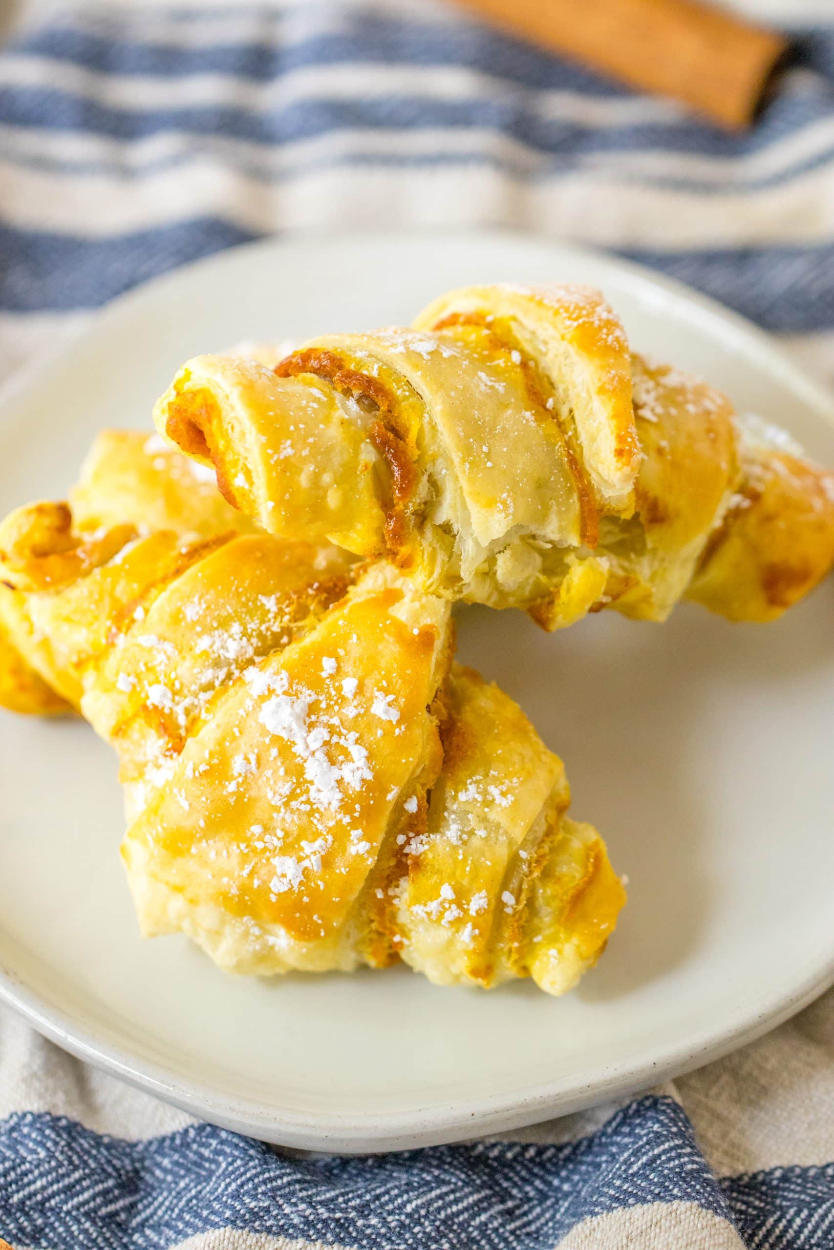 two pumpkin pie crescent rolls on a small white plate