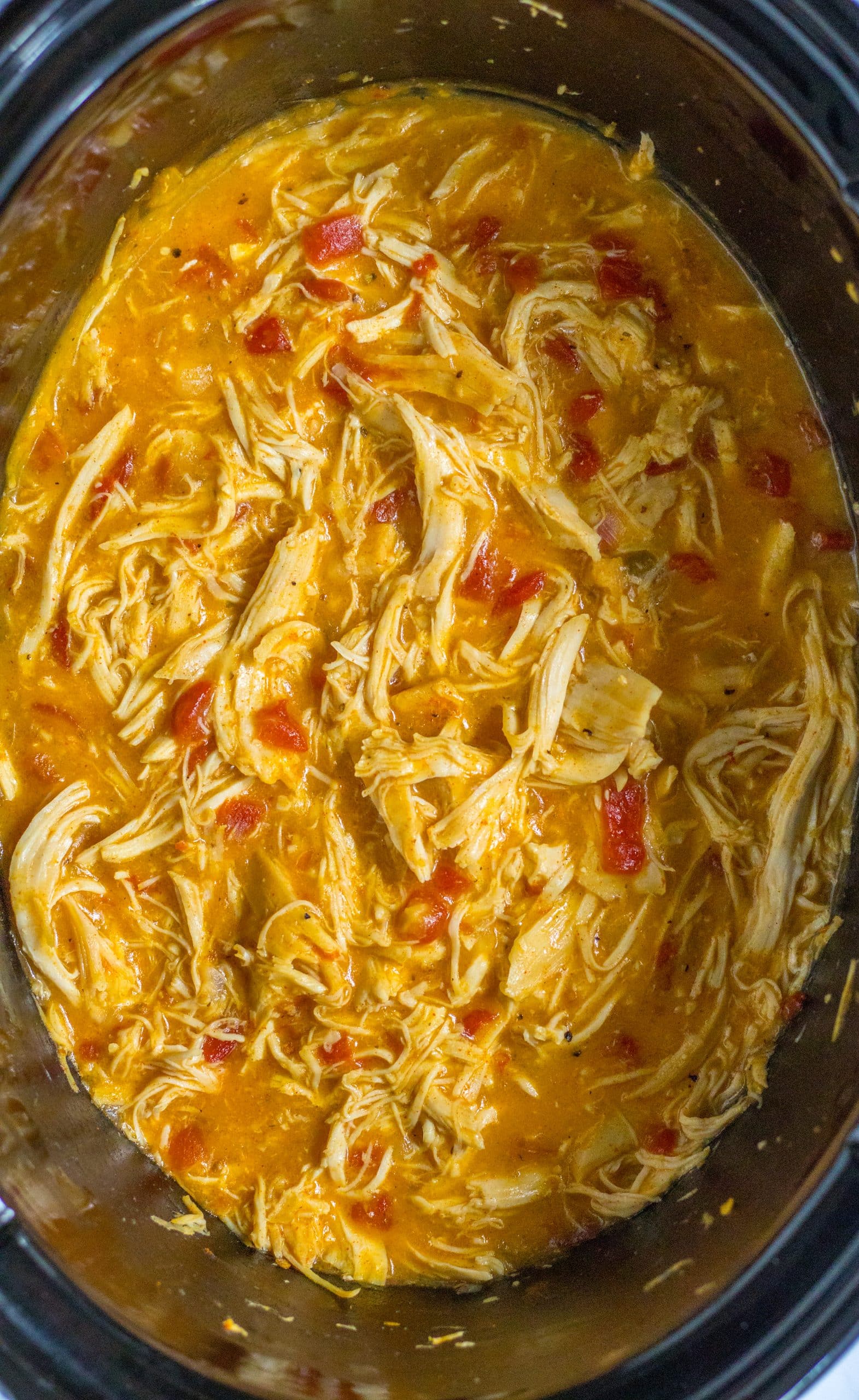 shredded cheesy chicken with rotel in a black slow cooker