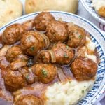 salisbury steak meatballs in gravy over mashed potatoes in a blue and white bowl