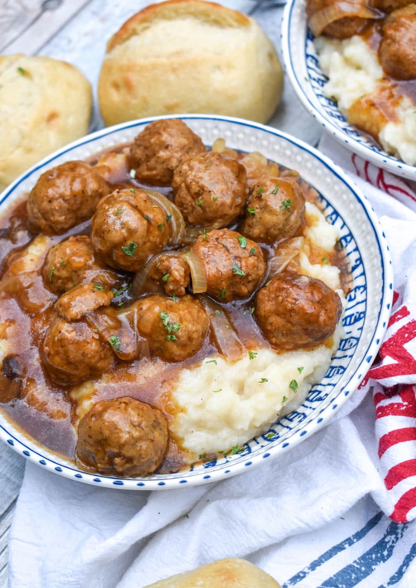 salisbury steak meatballs in gravy over mashed potatoes in a blue and white bowl