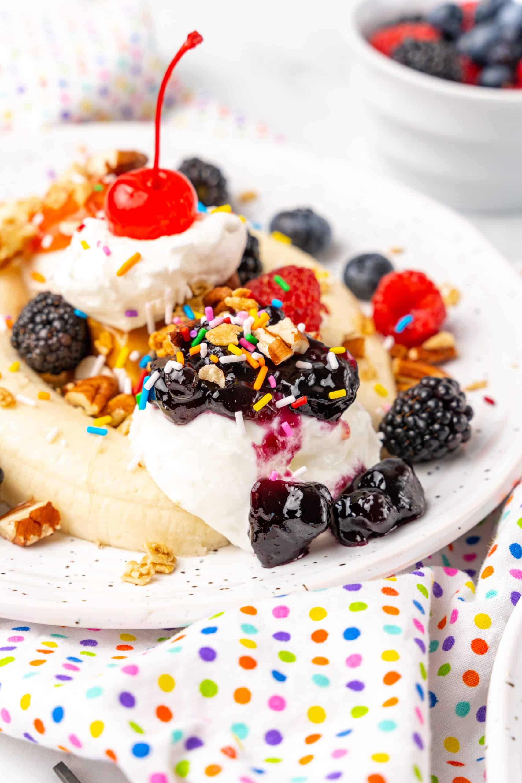 breakfast banana splits on white plates with fresh berries