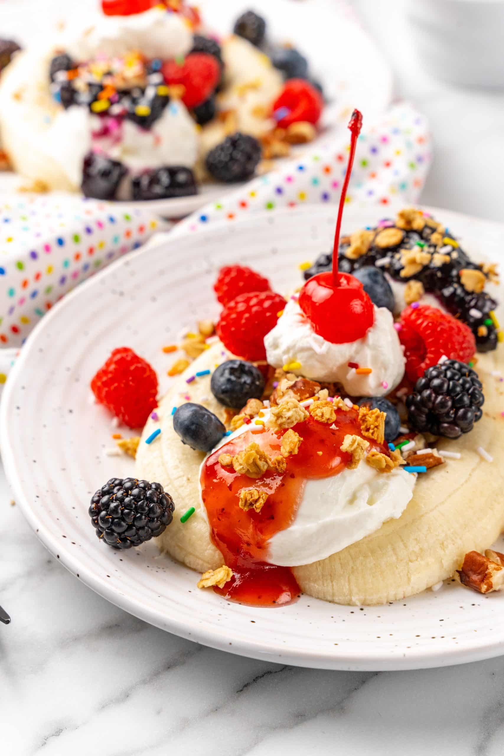 breakfast banana splits on white plates with fresh berries