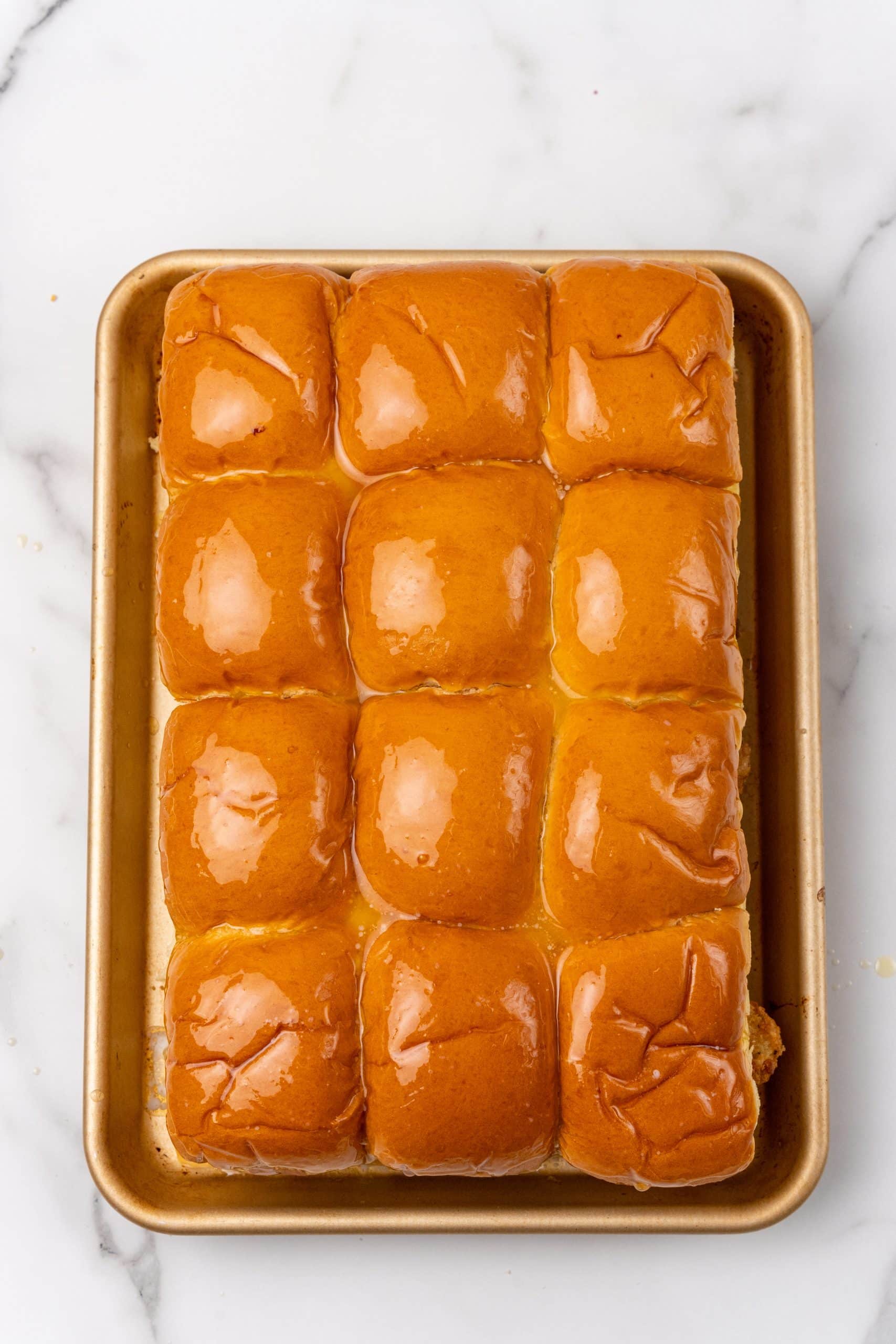 filet-o-fish sliders topped with melted butter on a metal sheet pan