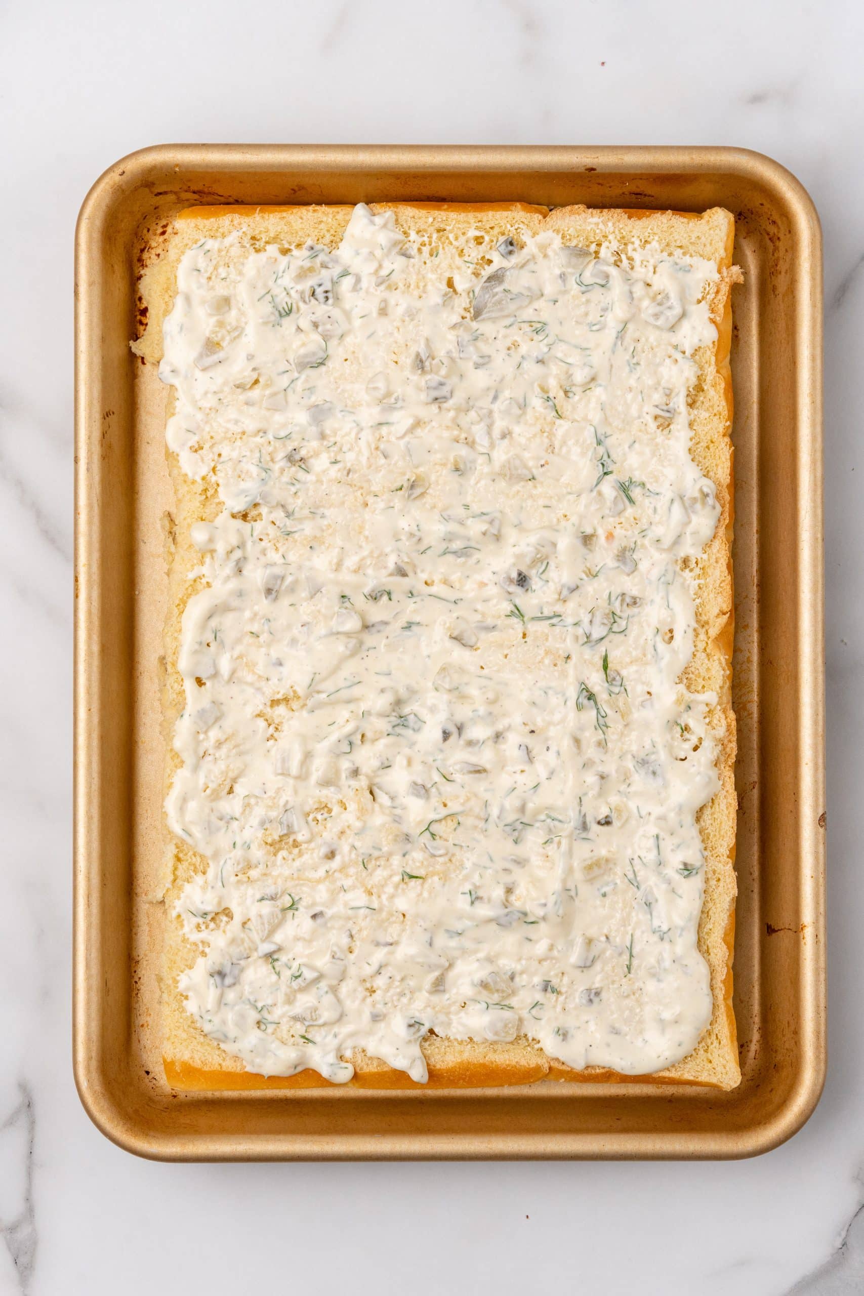 slider rolls spread with tartar sauce on a metal baking tray