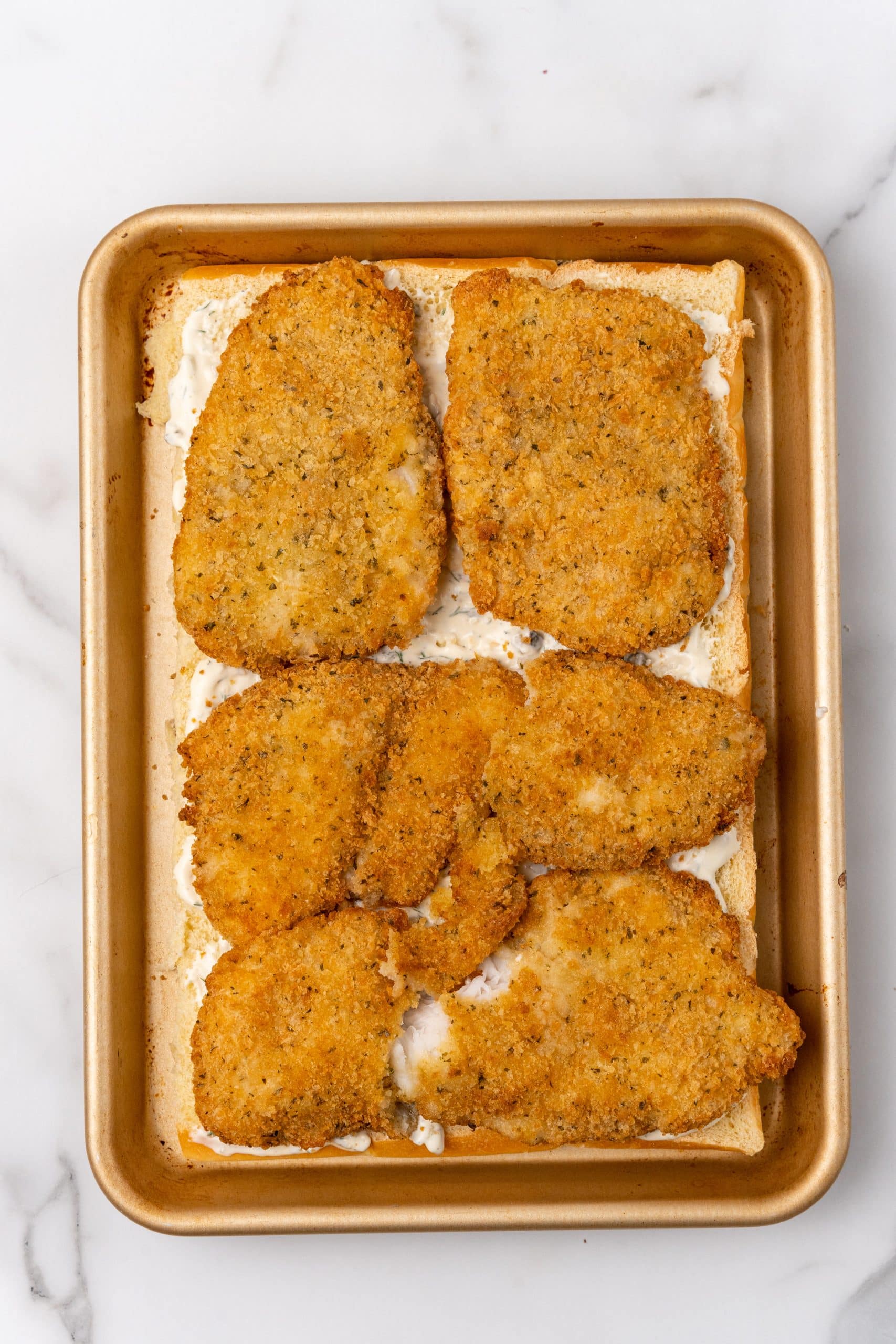 cooked breaded fish patties on top of slider buns