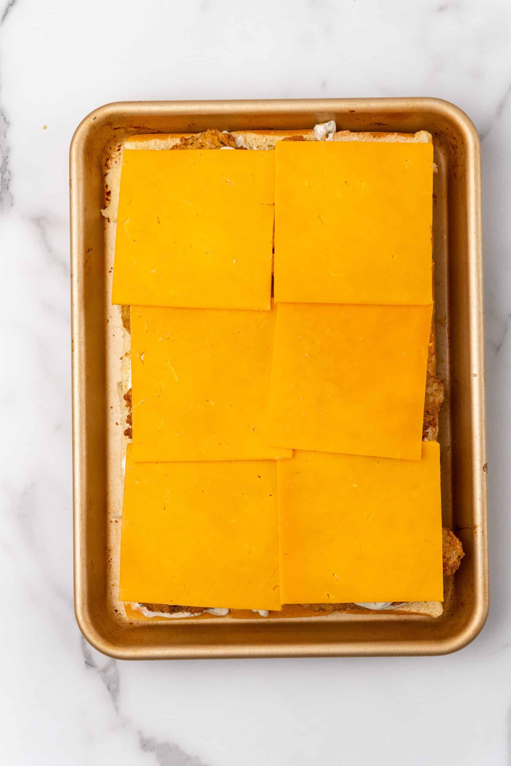 cheese topped filet-o-fish sliders on a metal sheet pan