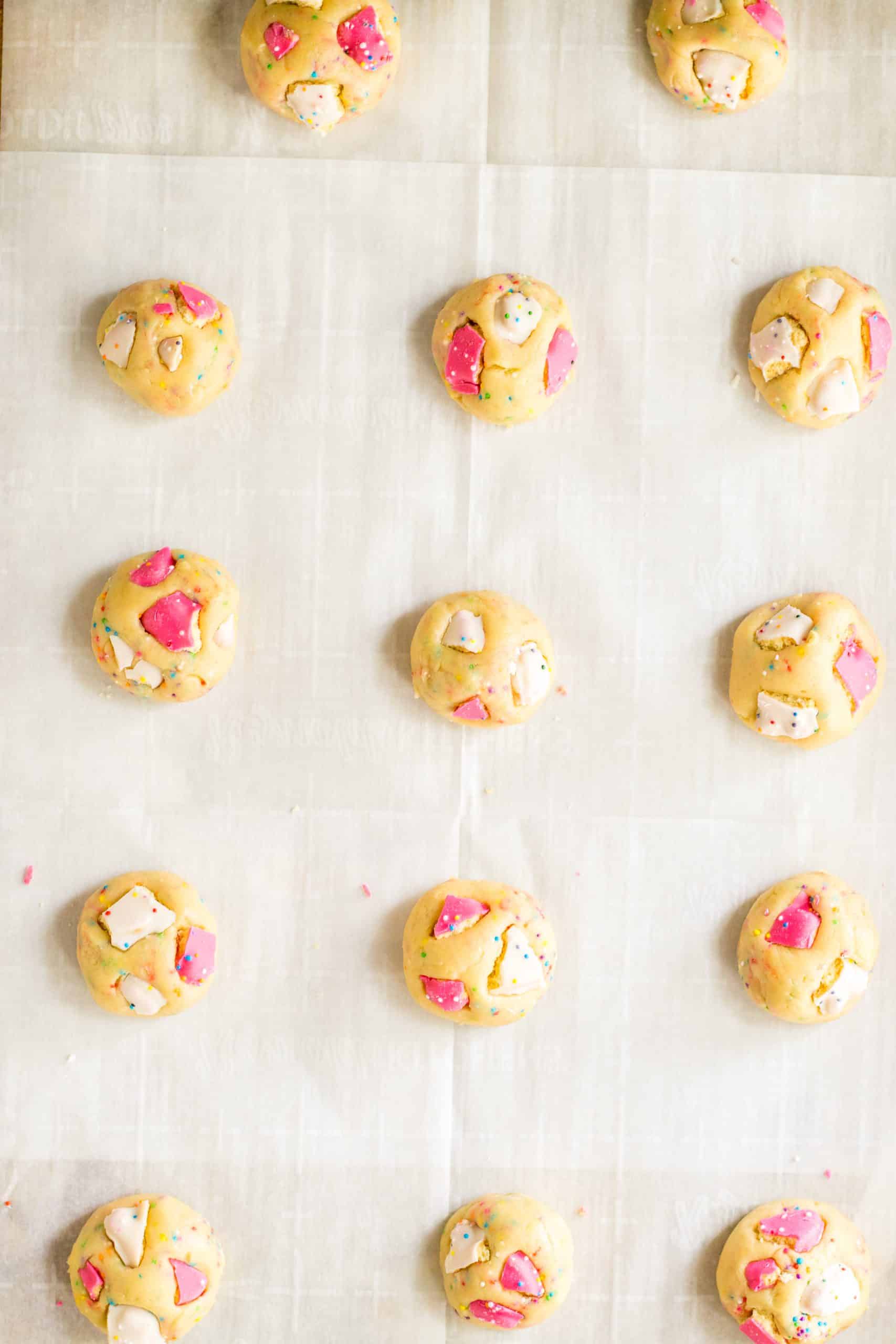 circus animal cookie dough balls arranged in rows on a parchment paper lined baking sheet