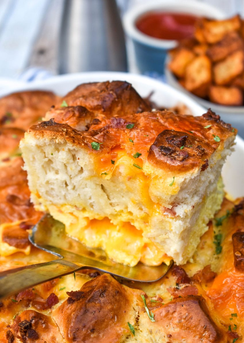 a slice of cheesy breakfast biscuit bake resting on a silver spatula