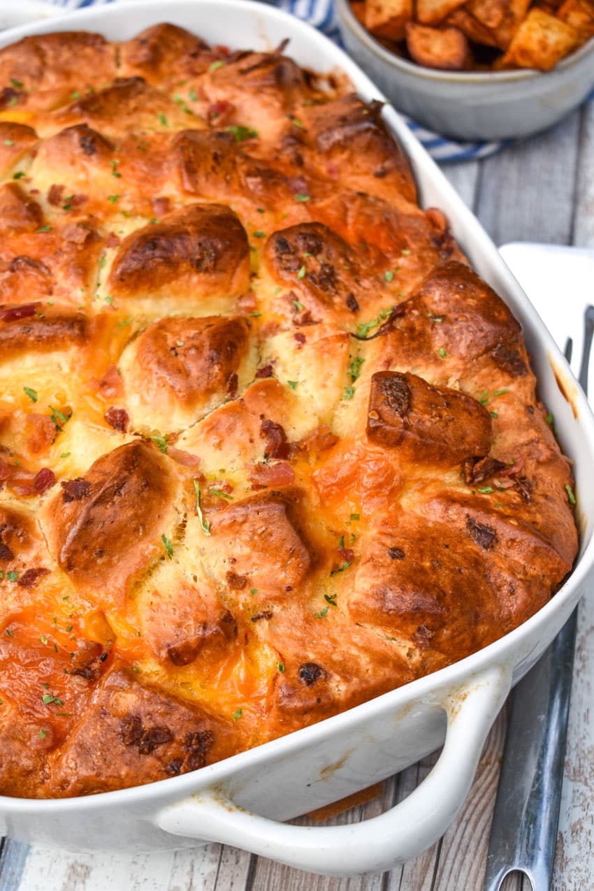cheesy bacon egg breakfast biscuit bake in a white casserole dish