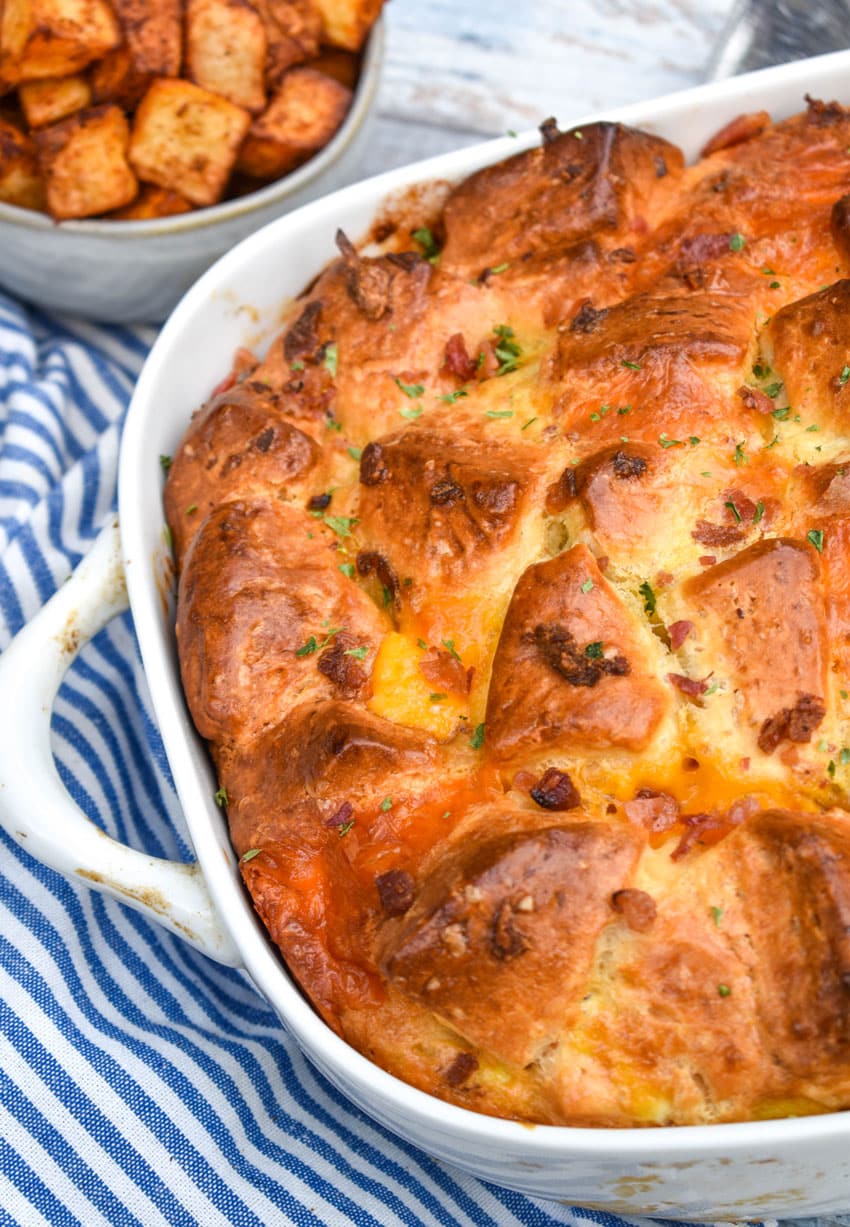 cheesy bacon egg breakfast biscuit bake in a white casserole dish