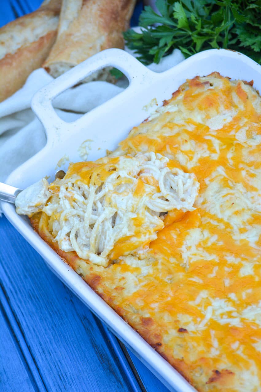a silver spoon scooping easy chicken tetrazzini out of a white baking dish
