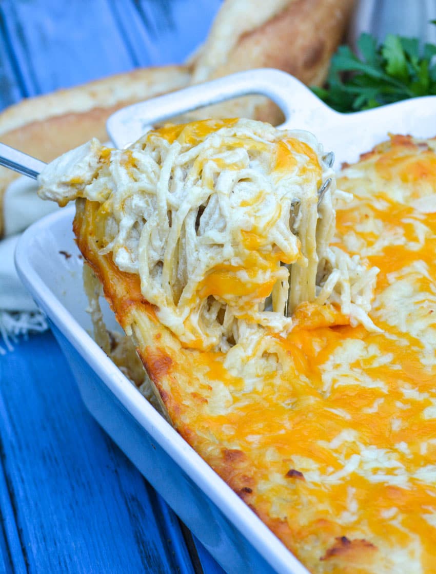 a silver spoon scooping easy chicken tetrazzini out of a white baking dish