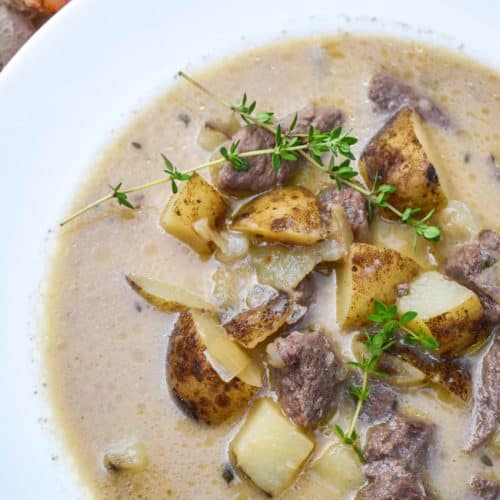 creamy steak and potato soup in a white soup bowl