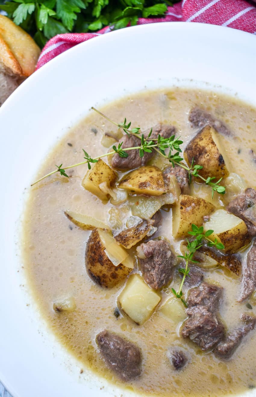 creamy steak and potato soup in a white soup bowl