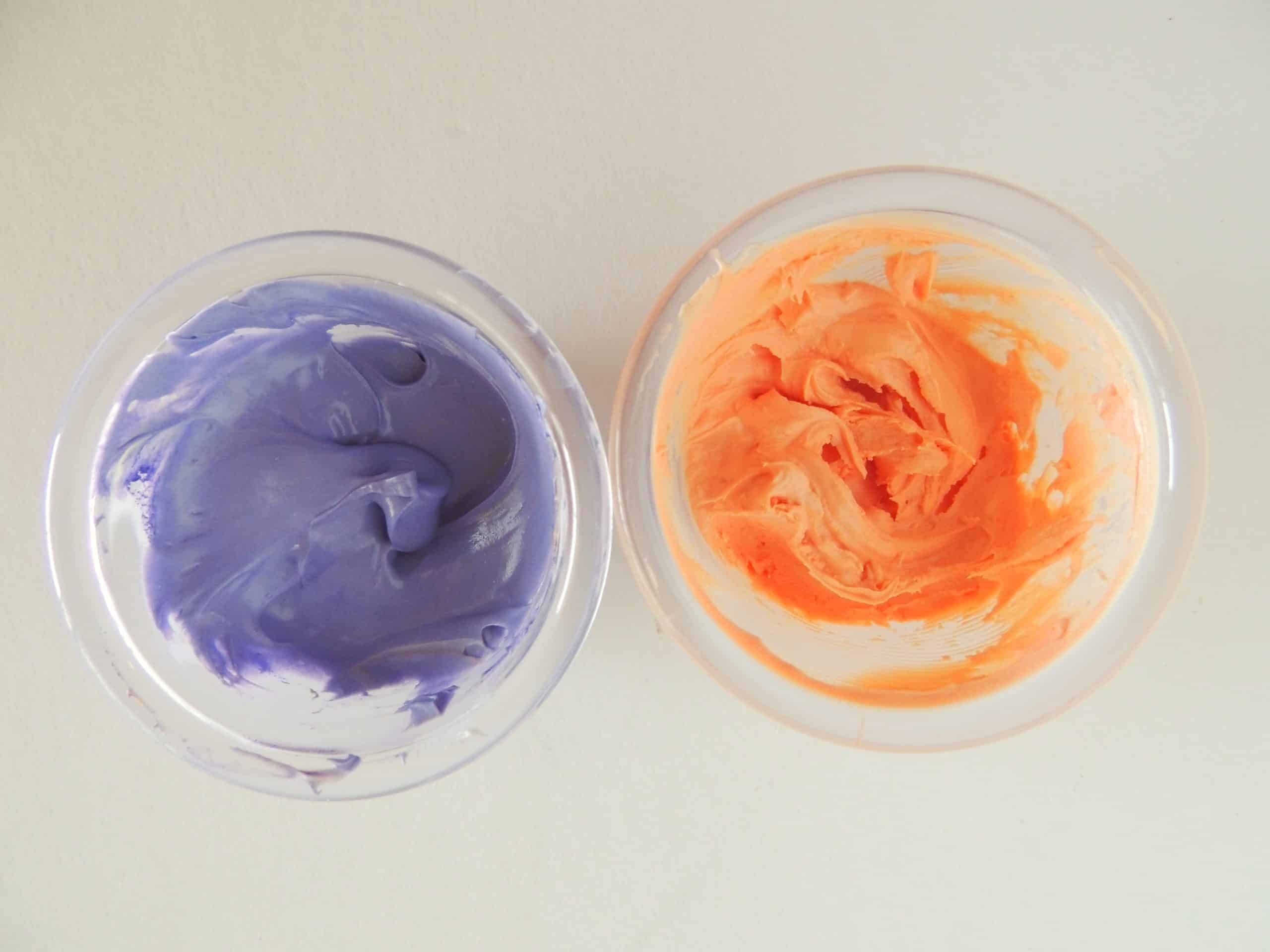 two bowls of dyed melted white chocolate- one orange and the other purple