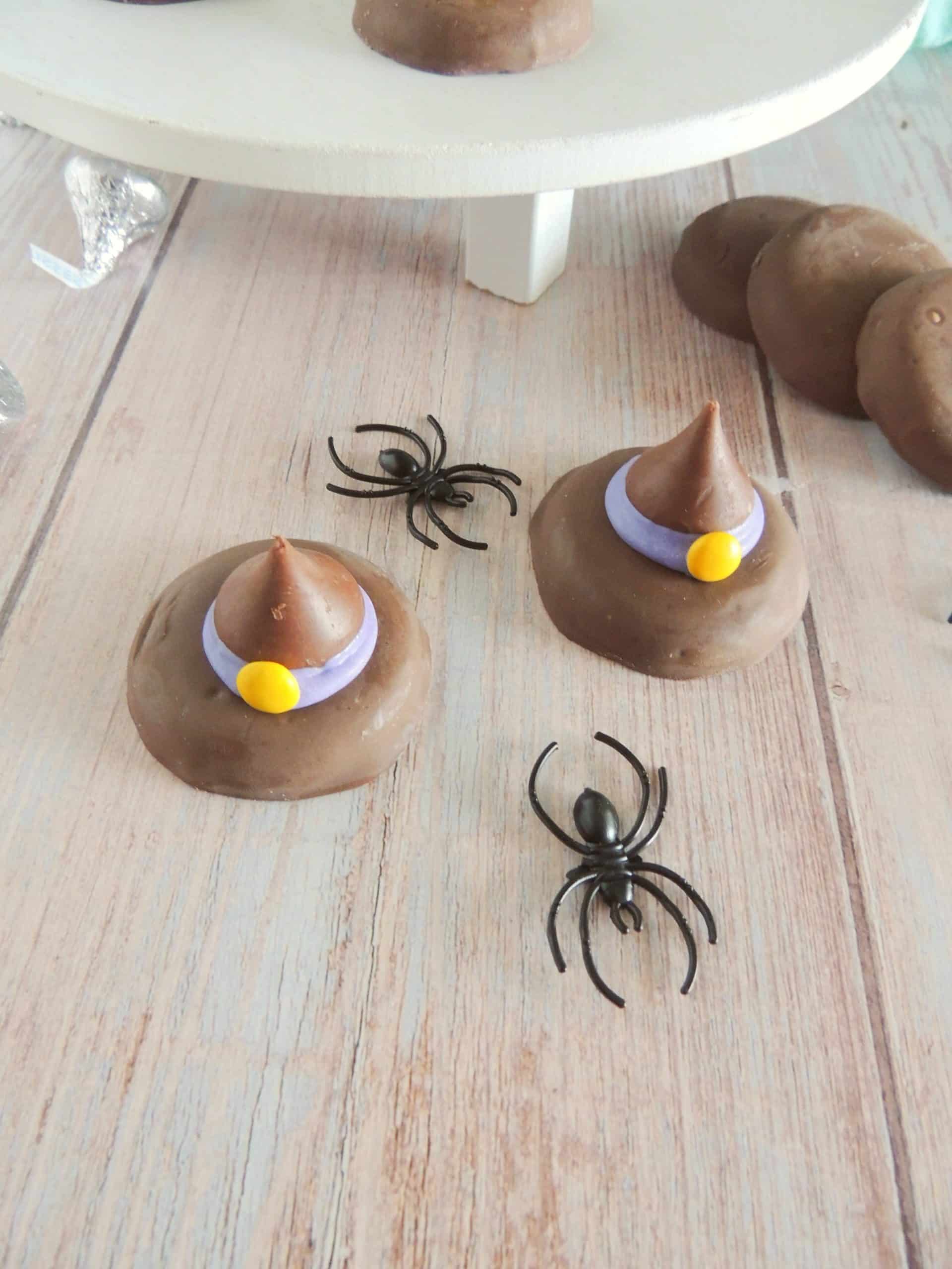 halloween witch hat cookies on a wooden table next to plastic black spiders