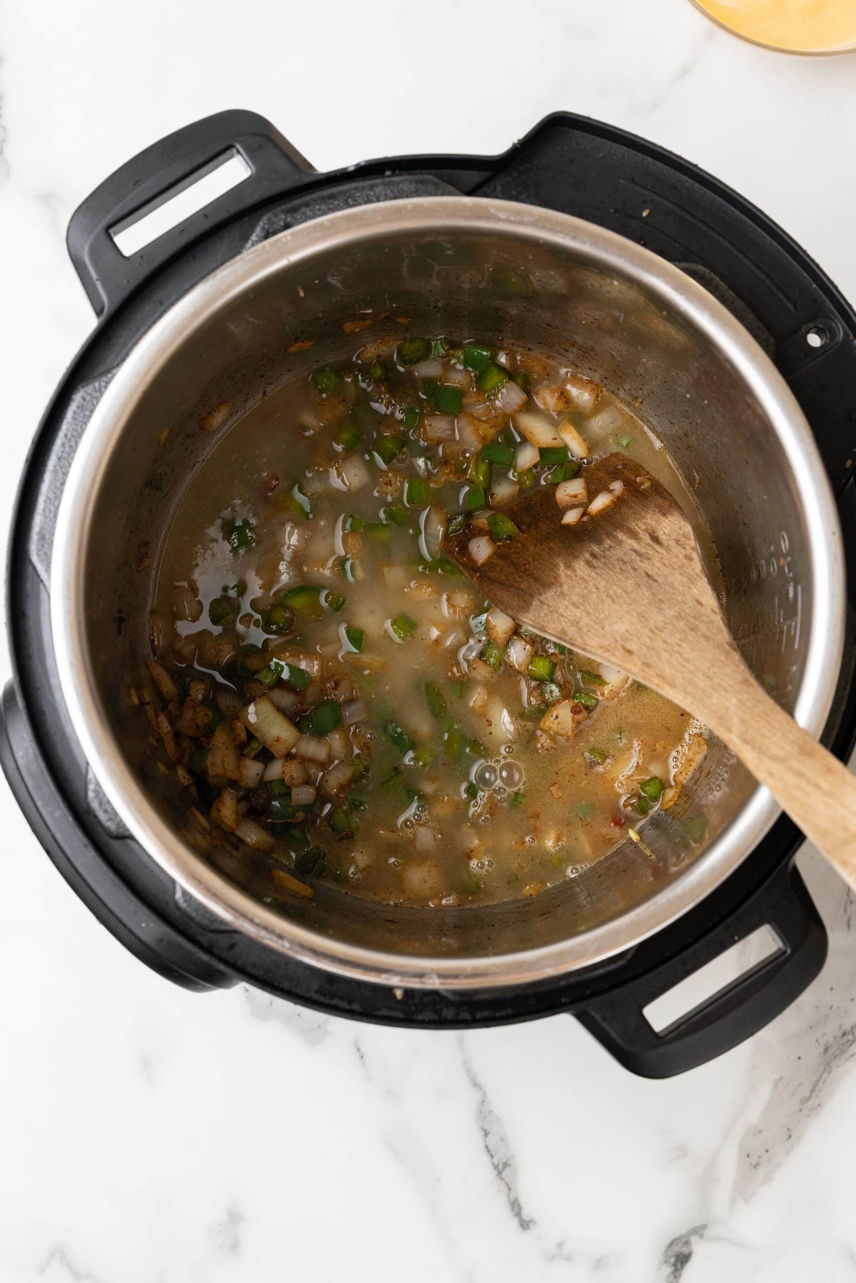 onions and peppers in chicken broth in the bowl of an instant pot