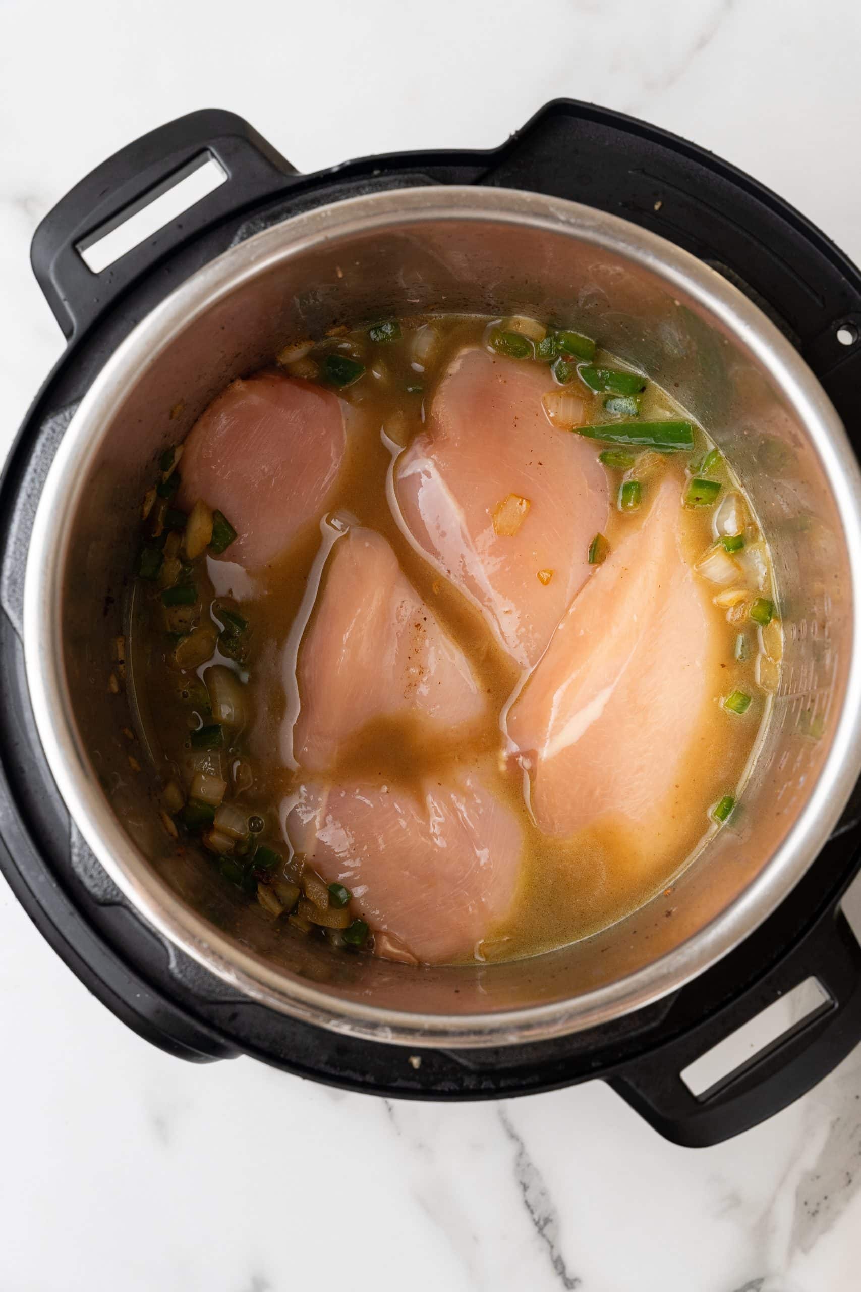 chicken breasts and veggies in chicken broth in the bowl of an instant pot
