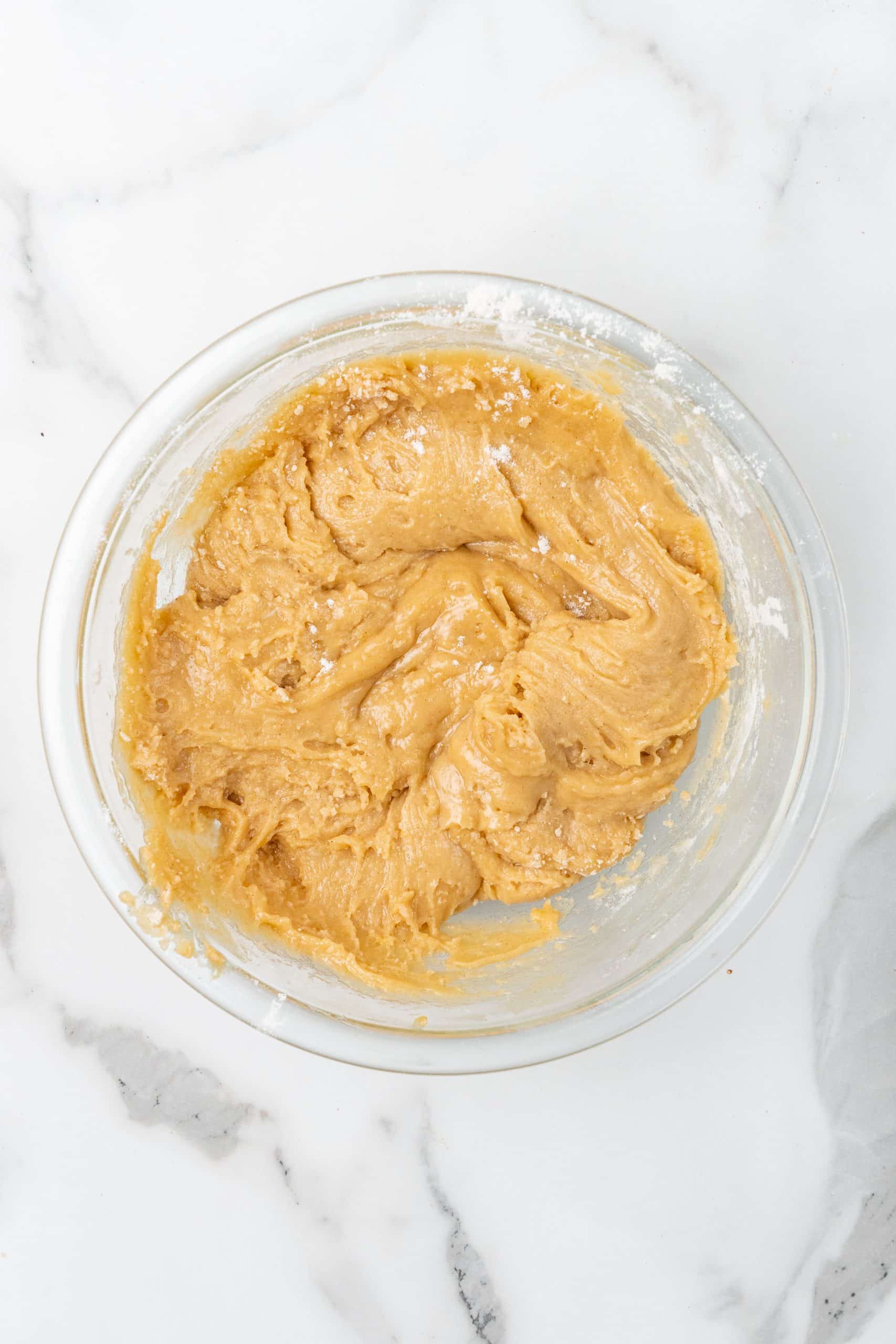 upside down apple cake batter in a glass mixing bowl