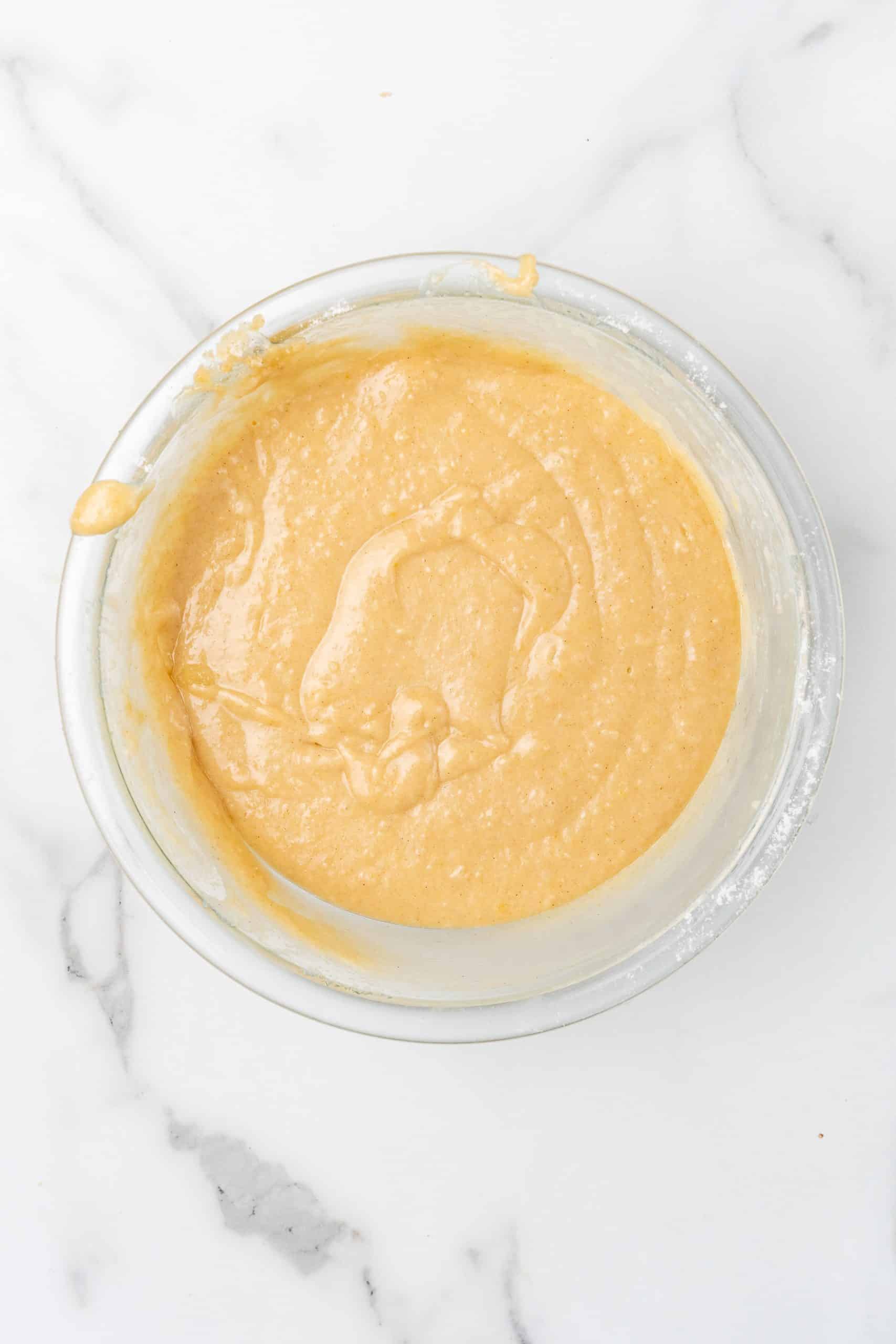 upside down apple cake batter in a glass mixing bowl
