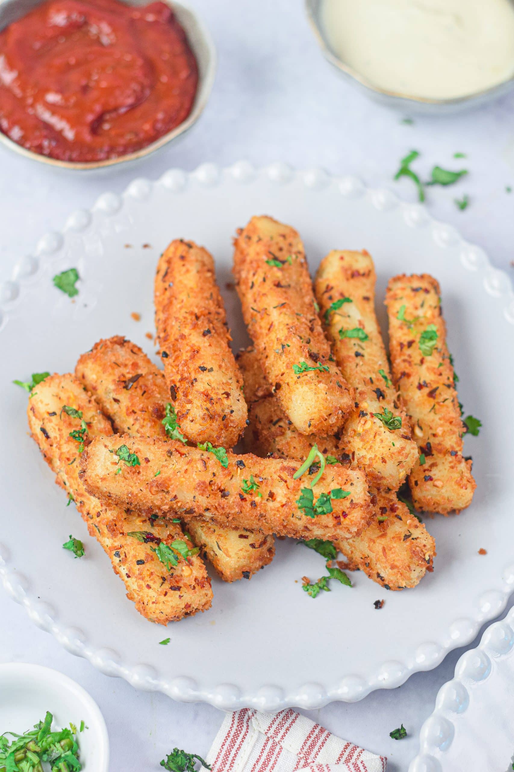 air fryer mozzarella sticks on a white plate with fresh herbs