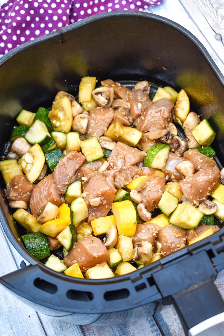 uncooked air fryer hibachi chicken and vegetables ingredients in an air fryer basket