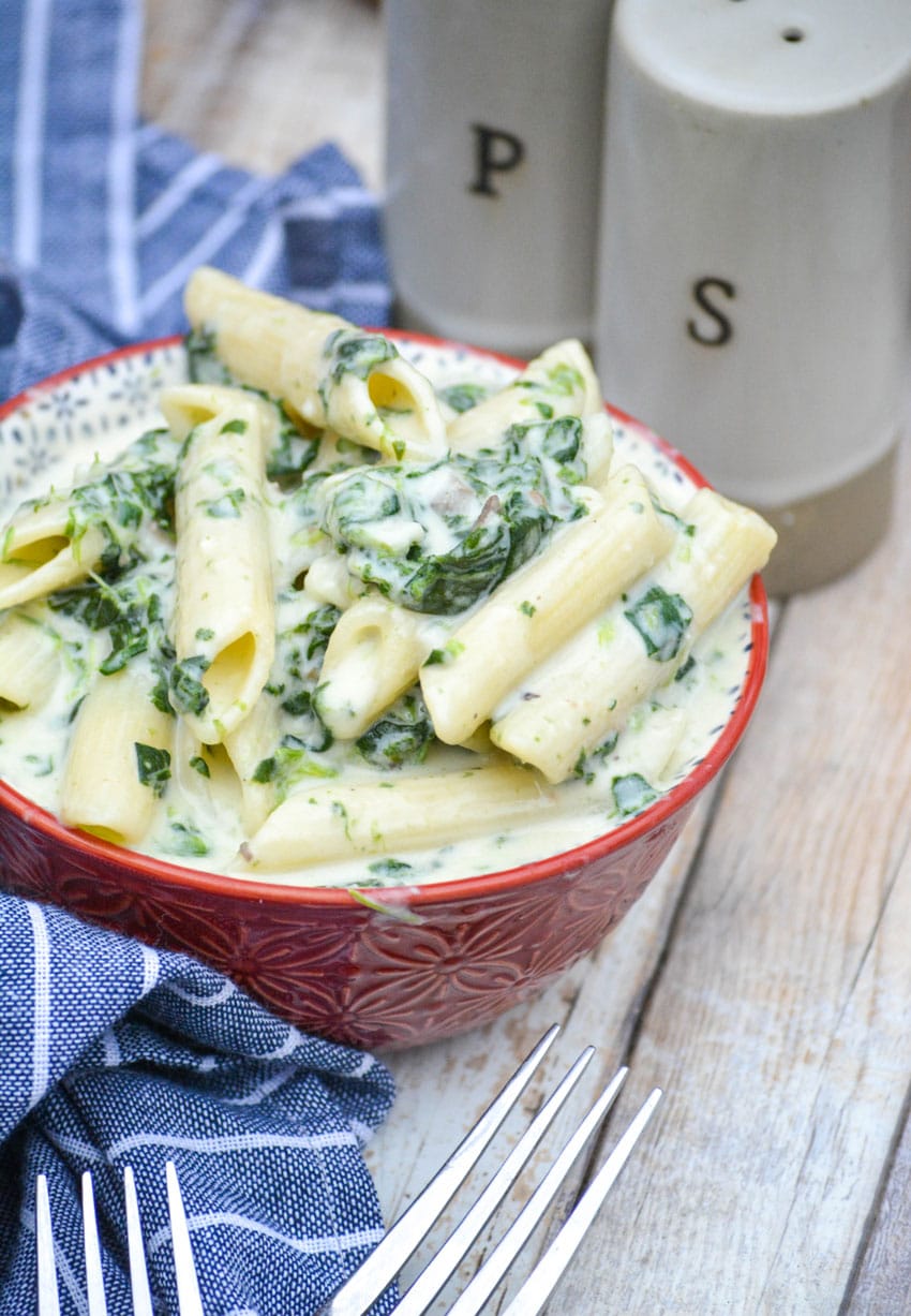 creamed spinach mac and cheese in a small red bowl