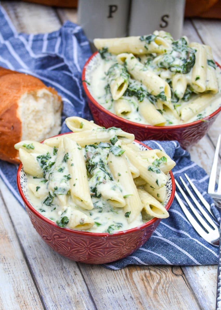 creamed spinach mac and cheese in two small red bowls