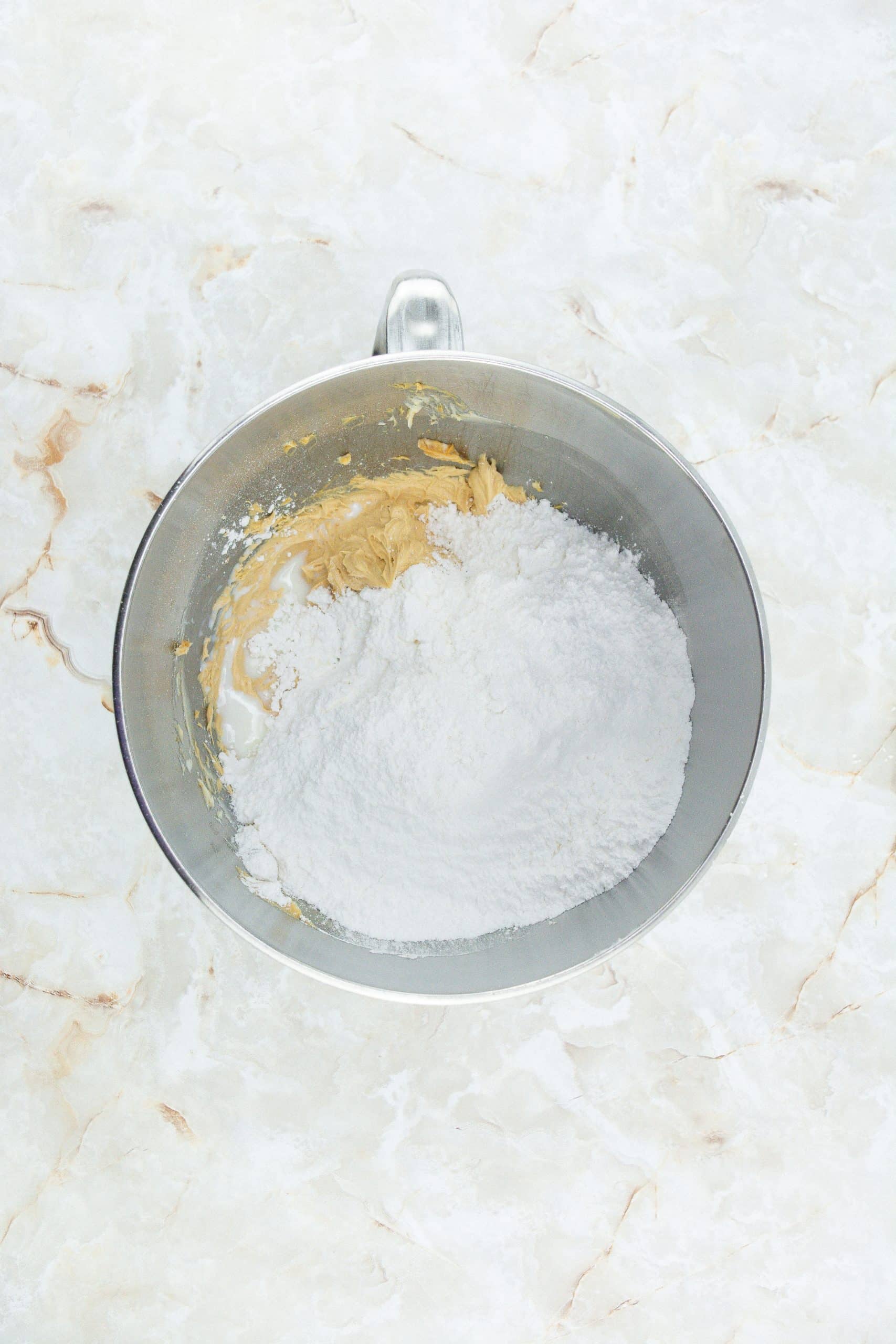 powdered sugar and creamed butter in a metal mixing bowl