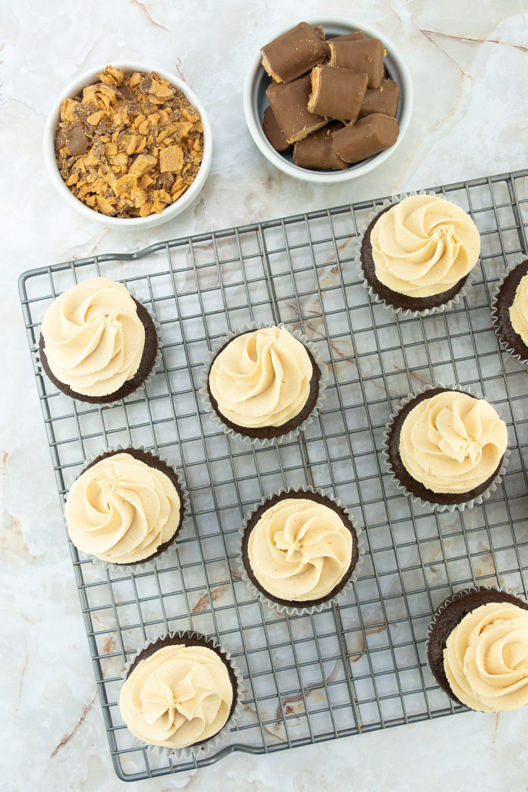 peanut butter frosting topped chocolate cupcakes on a metal cooling rack
