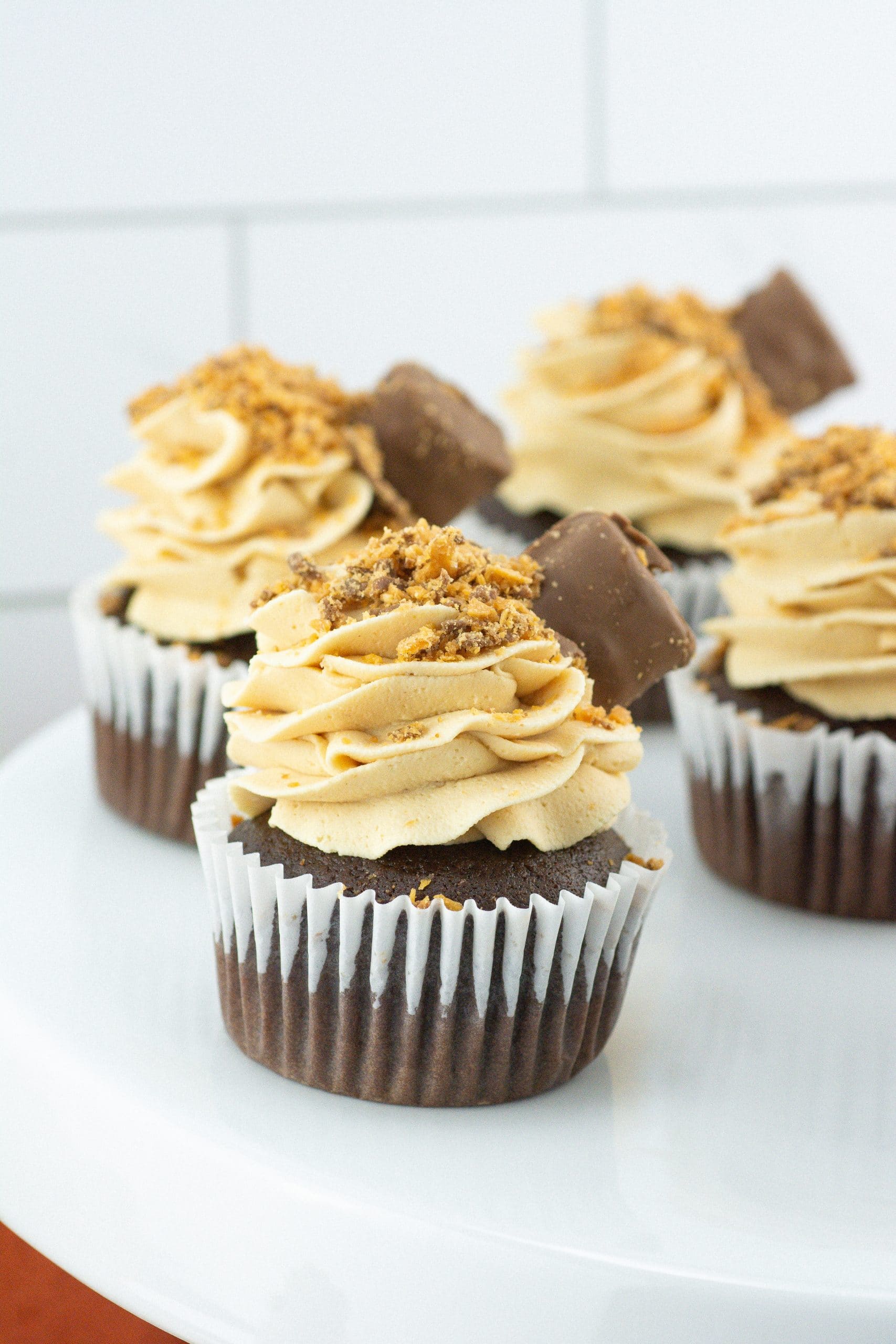 butterfinger cupcakes on a white cake stand