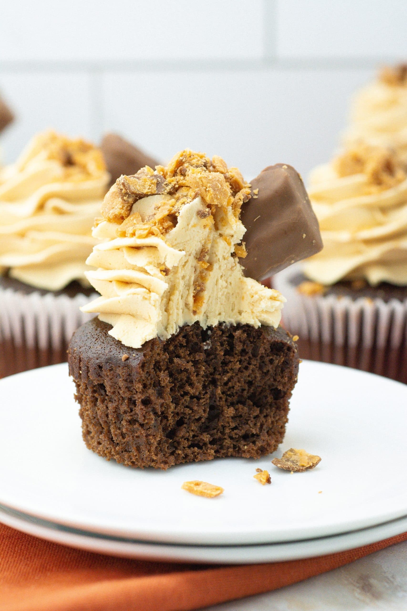 a bitten butterfinger cupcake on a white dessert plate