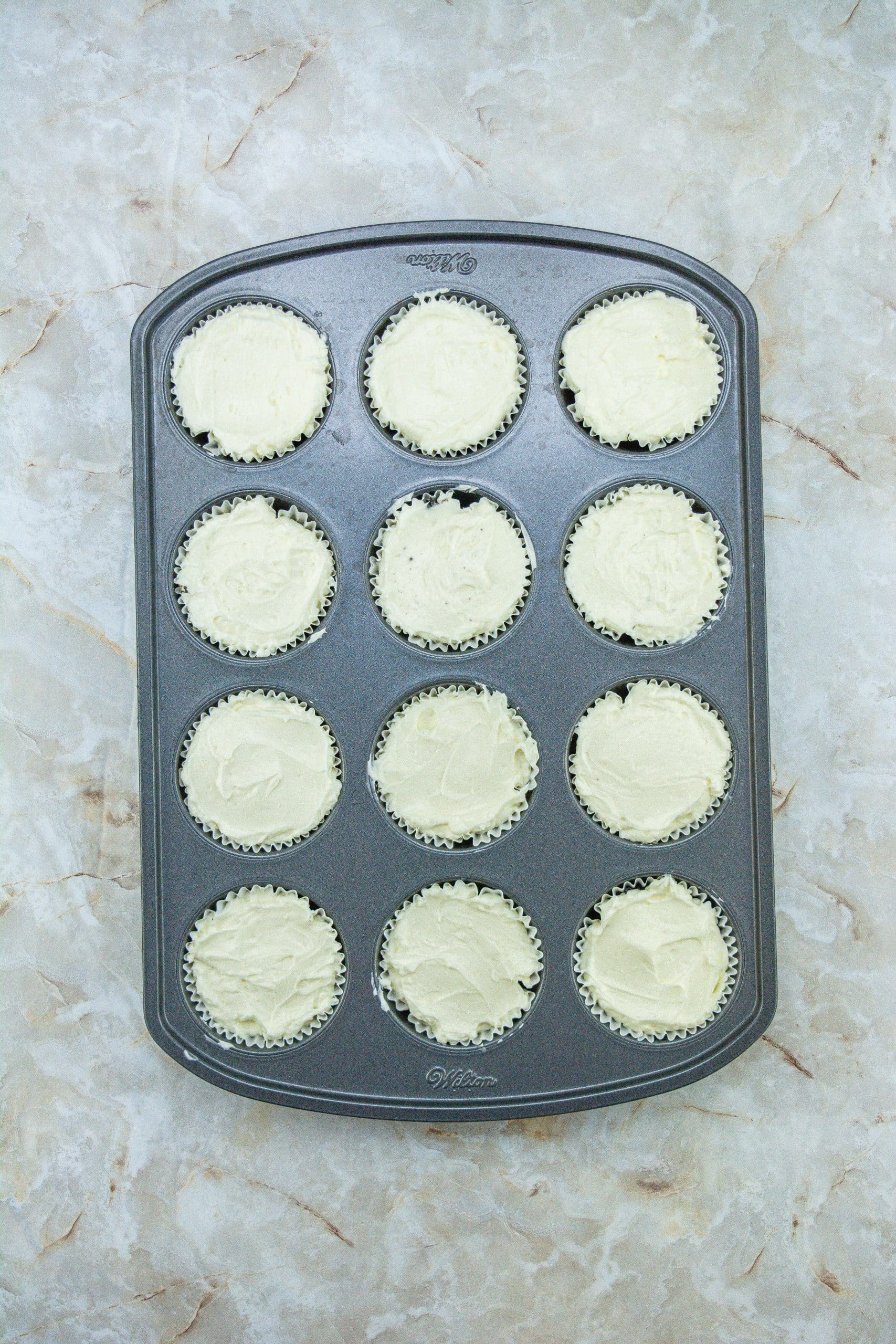 unbaked mini peppermint cheesecakes in a metal muffin tin