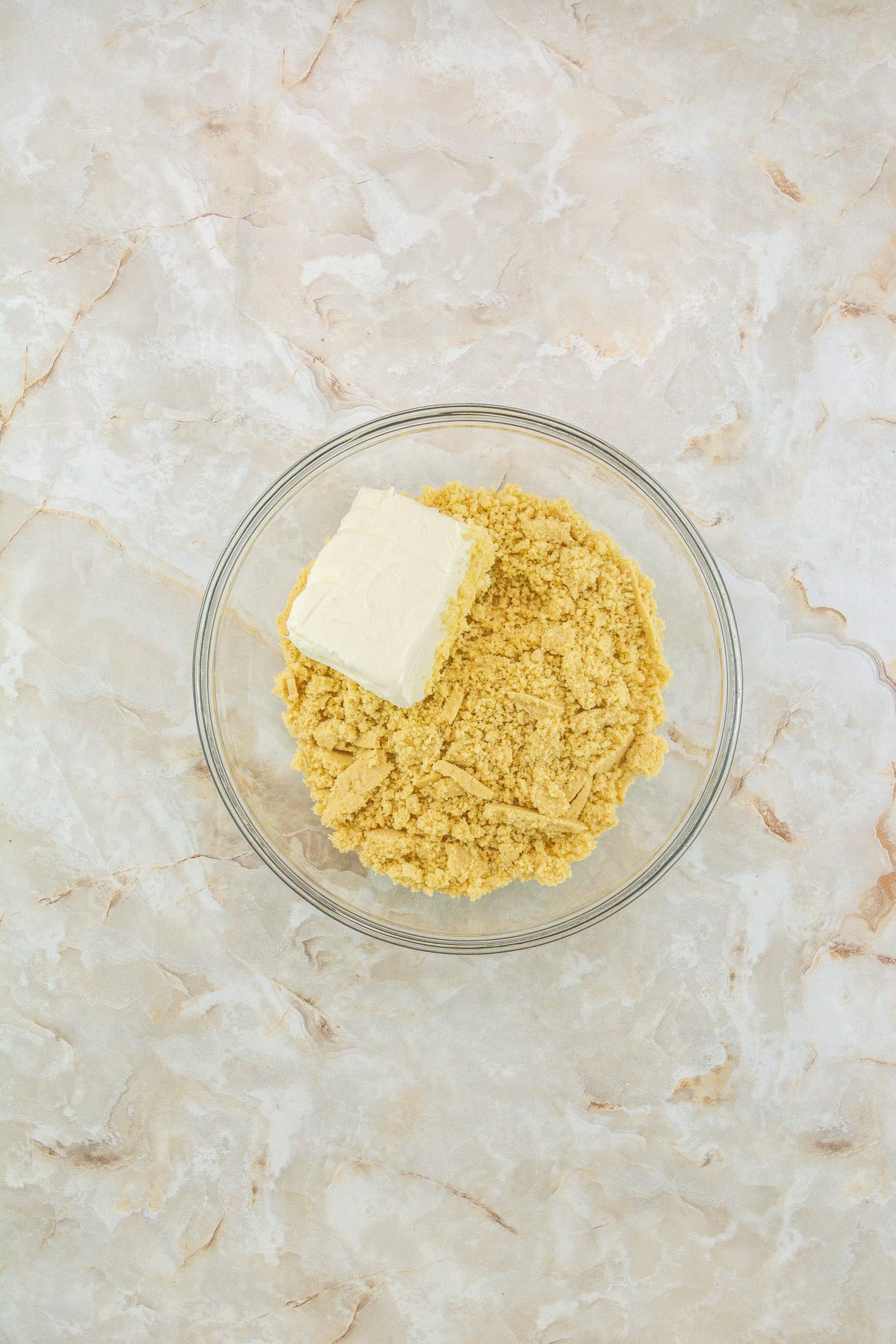 crushed oreos and butter in a glass mixing bowl