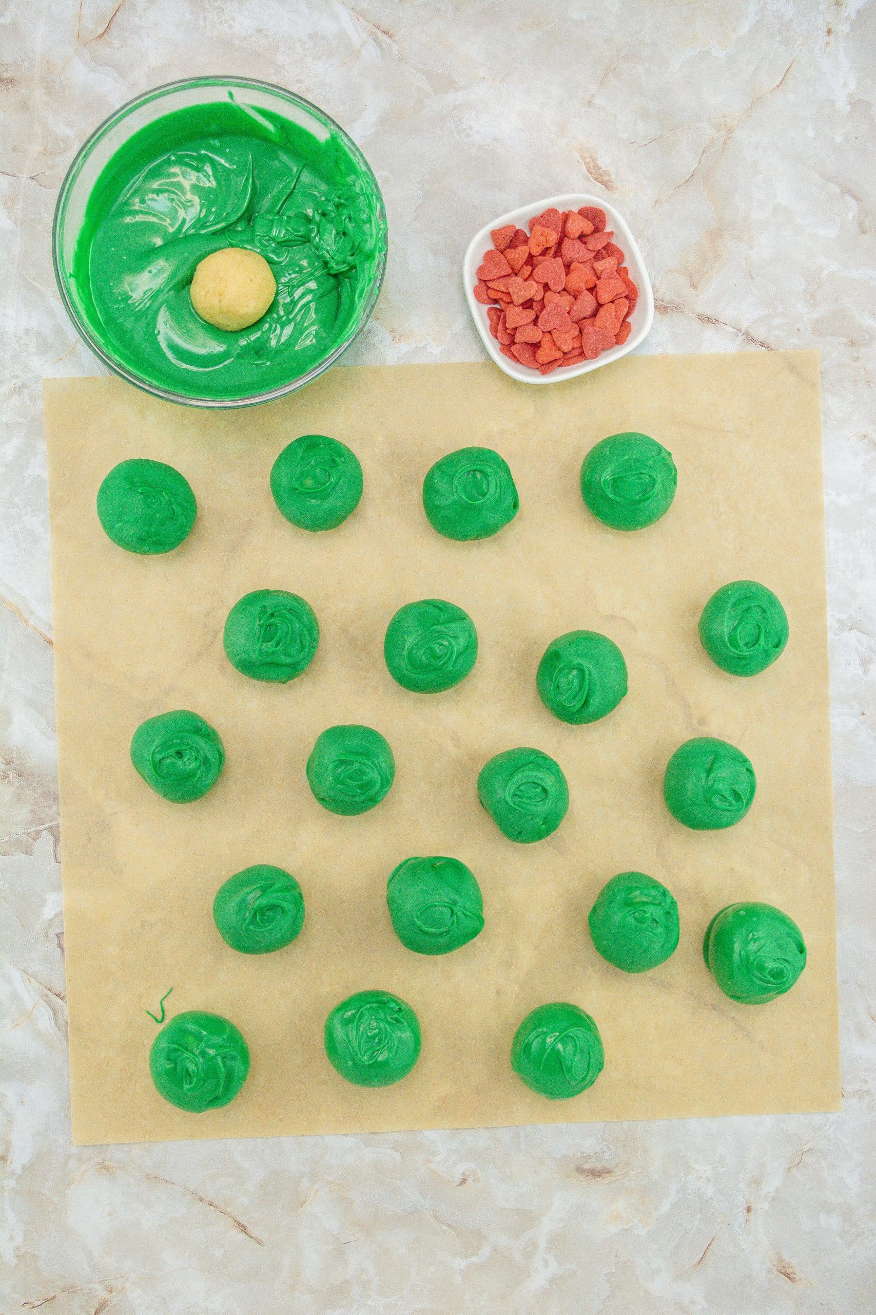 grinch truffles arranged in rows on a sheet of brown parchment paper